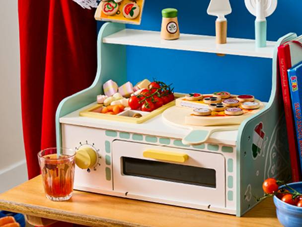 Houten speelkeuken met pizza, groenten en kookgerei op een houten tafel.