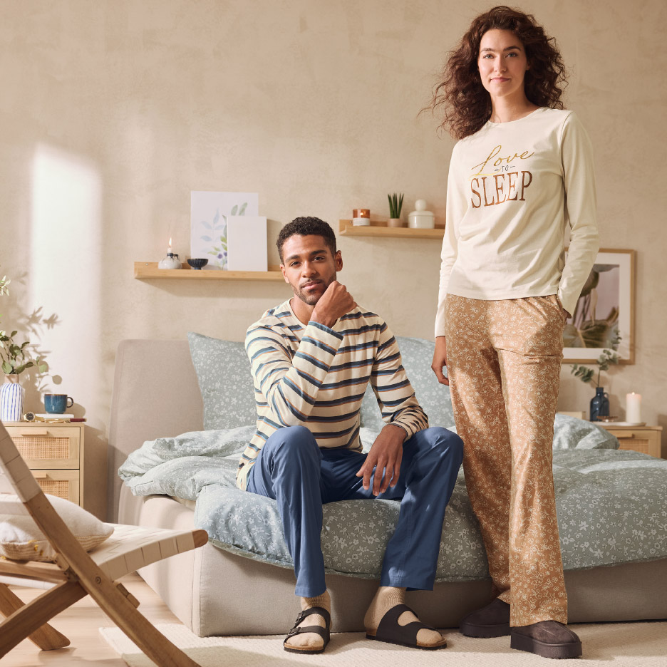 Man en vrouw in pyjama's in een slaapkamer. De vrouw draagt een pyjama met 'Love to Sleep' erop.