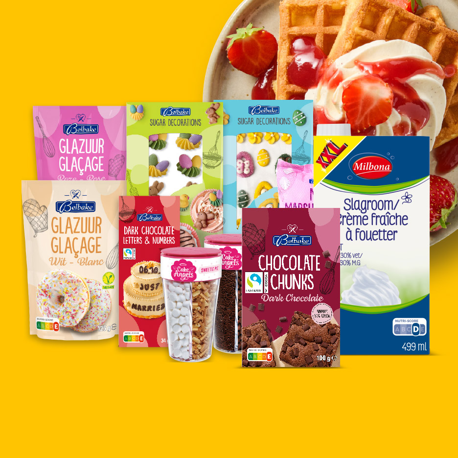 Een assortiment bakproducten, waaronder glazuur, chocoladeletters, decoraties en slagroom, met wafels op de achtergrond.