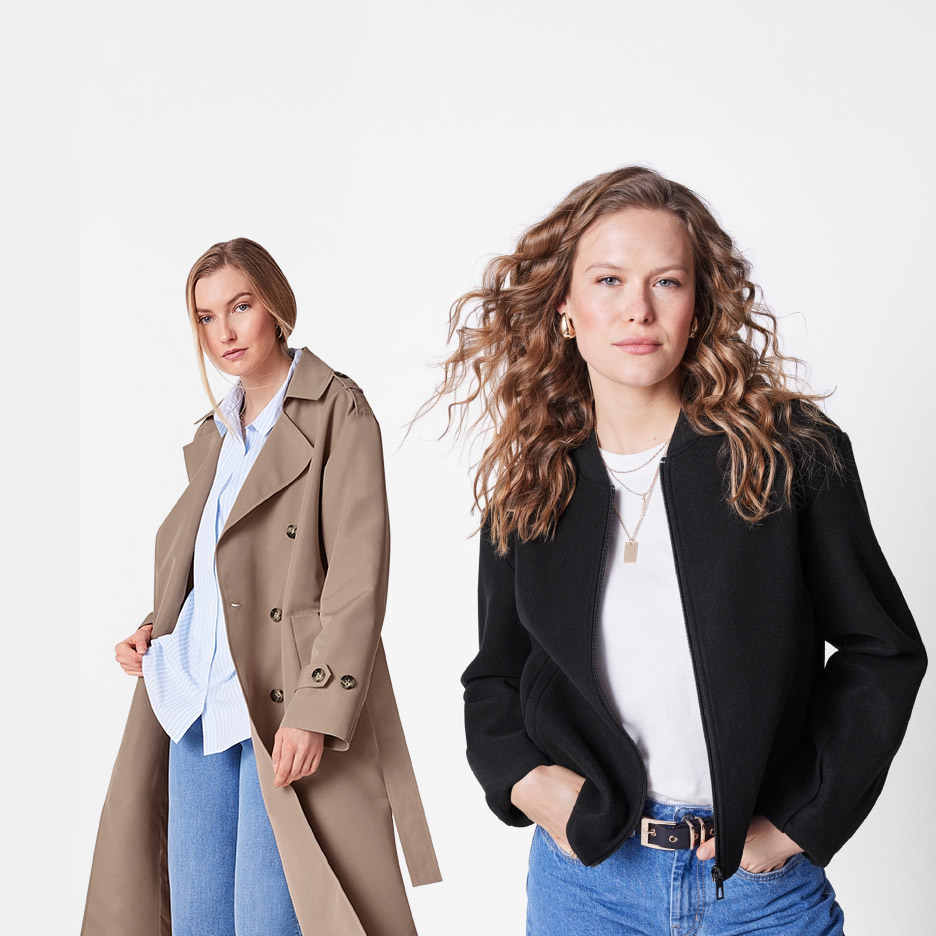 Twee vrouwen dragen een beige trenchcoat en een zwart bomberjack met jeans.
