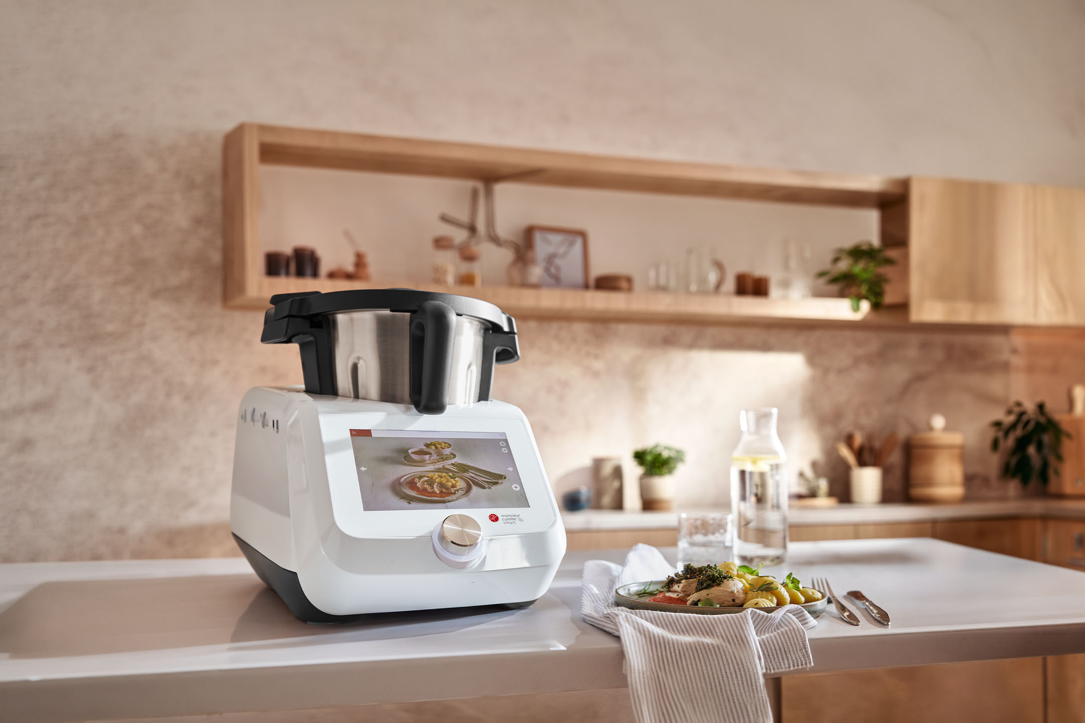 Keukenmachine met bereid gerecht op tafel in een lichte keuken.