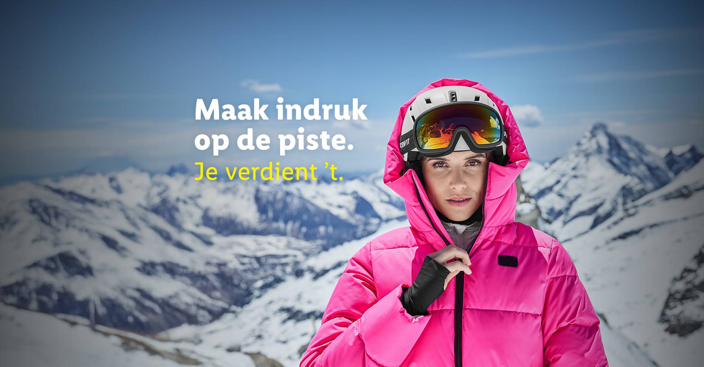 Vrouw in roze ski-jas en skihelm met skibril, met besneeuwde bergen op de achtergrond. Tekst: 'Maak indruk op de piste. Je verdient 't.'